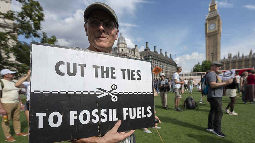 Man outside Parliament with sign