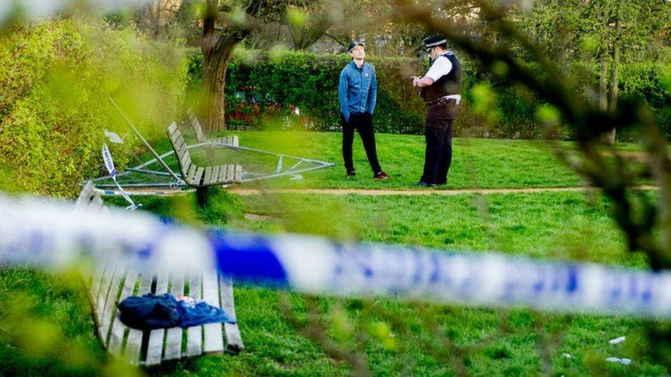 A police officer and a man at a sealed off area of a park