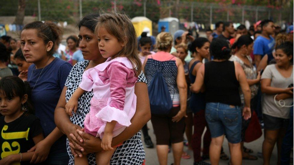 A female migrant holds her young daughter at makeshift camp in Mexico