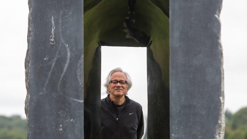 Artist Anish Kapoor looks through one of his sculptures at Houghton Hall