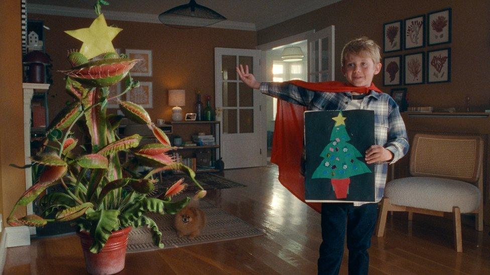 Young boy standing next to festive Venus-Flytrap