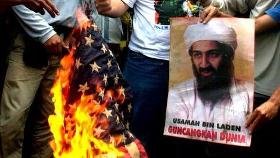 Anti-US protesters burn an American flag next to a portrait of Osama bin Laden in front of the U.S. embassy in Jakarta, Indonesia, Tuesday, Oct. 9, 2001.