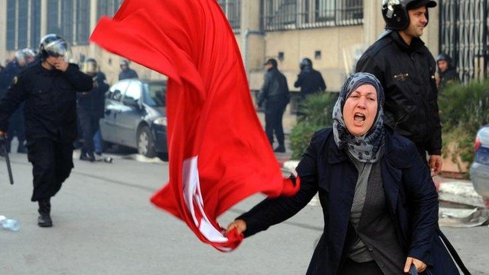 A woman waves Tunisia's national flag during clashes with police in the capital Tunis. Photo: 14 January 2011