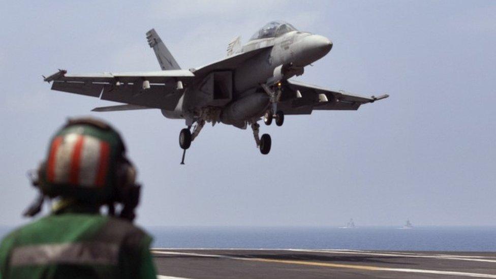 A US Navy fighter jet approaches to land on the aircraft carrier USS Theodore Roosevelt (17 October 2015)