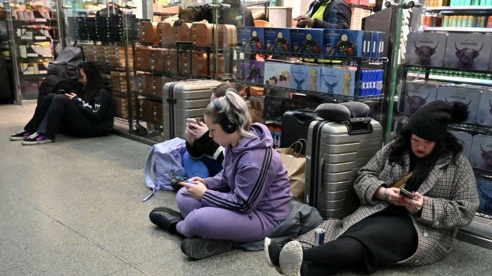 Passengers wait with their luggage at St Pancras station