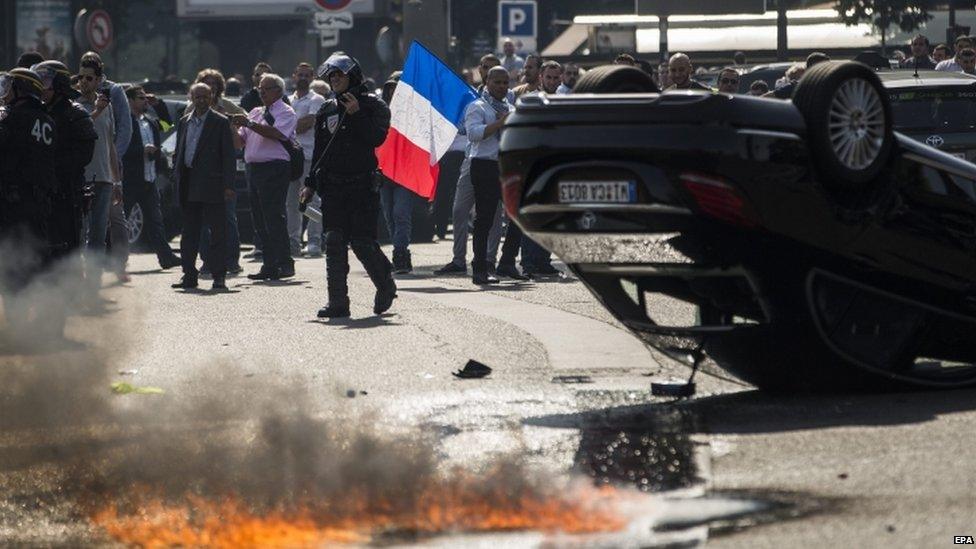 An UberPop vehicle overturned by French taxi drivers as they clash with riot police