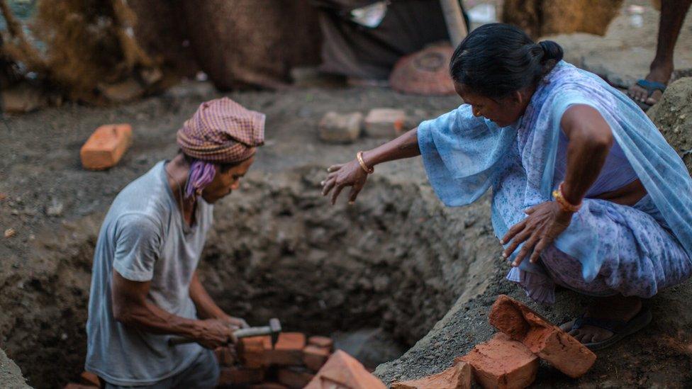 A woman clad in a sari helps a mason build a toilet in India's Kanpur city in 2014.