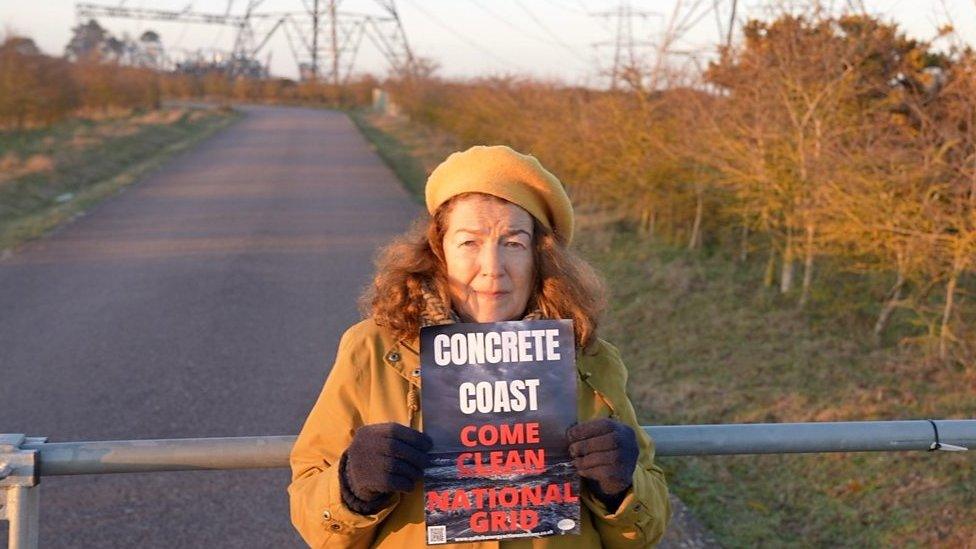 Campaigner Fiona Gilmore holds up a placard reading 'Concrete Coast: Come Clean National Grid'.