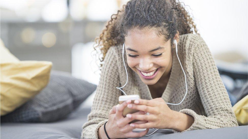 Young woman on her phone with earphones in