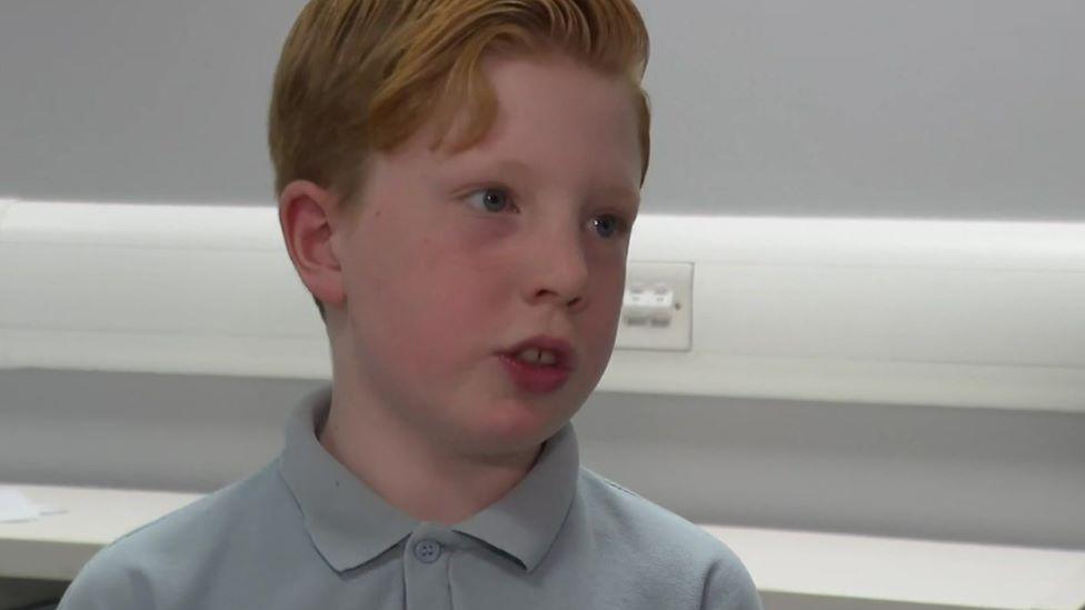 Stanley wearing his school uniform and looking away from camera towards the reporter