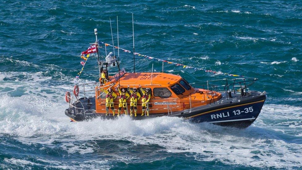 RNLI lifeboat at sea with crew waving