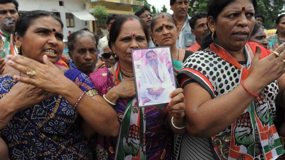 Congress workers hold up a portrait of self-styled godman Asaram Bapu as they shout slogans against him during a protest in the Amraiwadi area of Ahmedabad on August 31, 2013