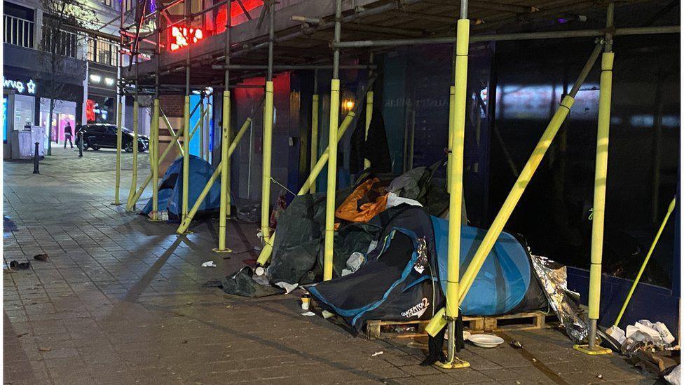 A number of tents pitched beneath a set of scaffolding on a city centre street in Liverpool