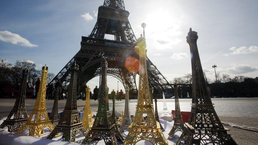 Miniatures of the Eiffel Tower are sold as souvenirs on a street of Paris at the foot of the monument