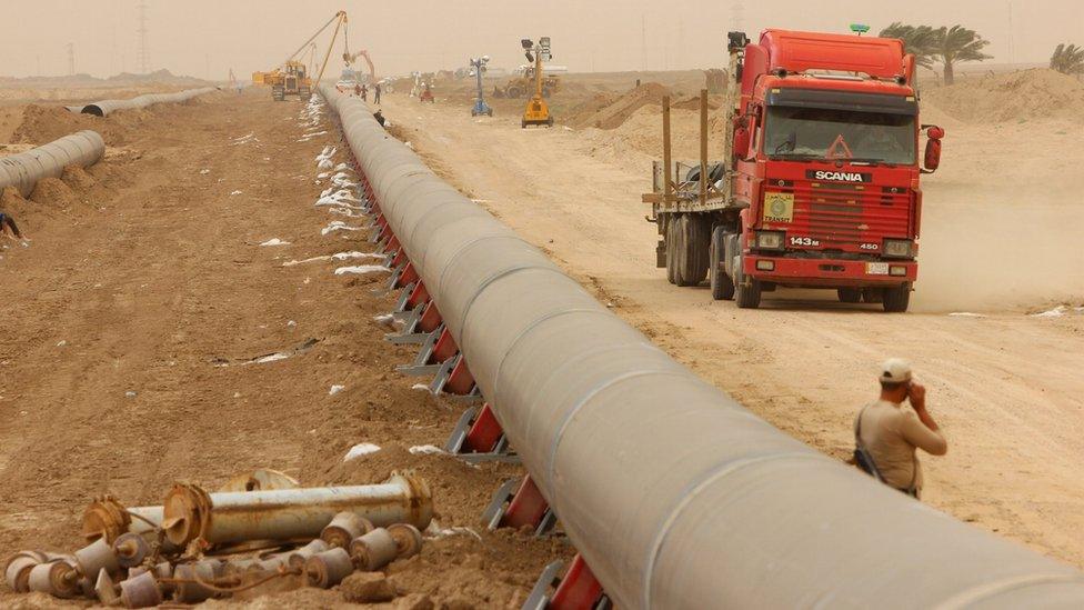 Workers set up a natural gas pipeline during a dust storm at Iraq's border with Iran in Basra