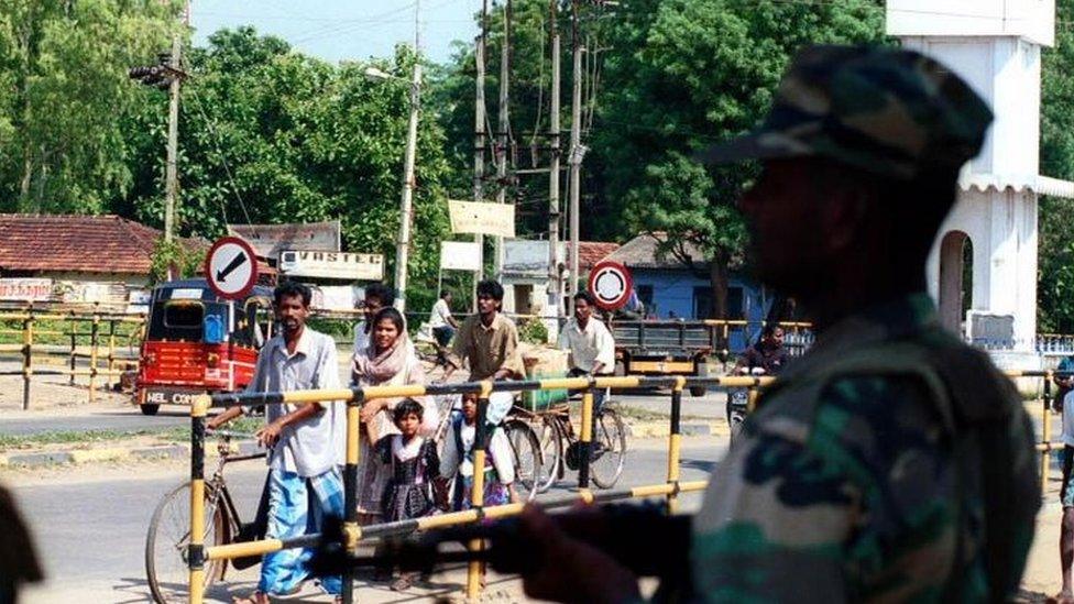 A Sri Lankan army soldier looks on as civilians walk out of Vavuniya town, 210 kilometres (130 miles) north of the capital, Colombo, Thursday November 11, 1999.