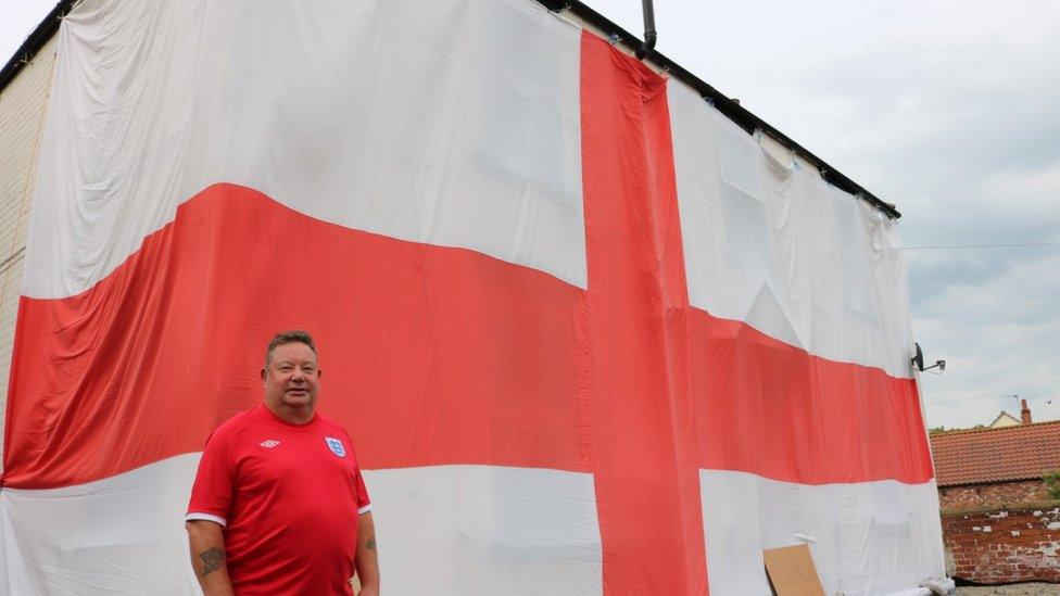 John Jupp standing in front of his huge England flag