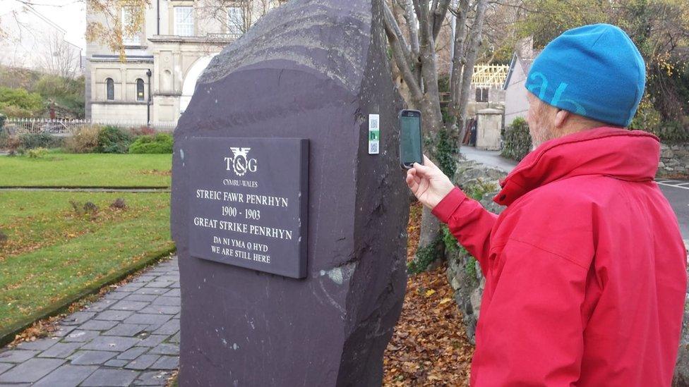 Strike memorial stone in Bethesda with a HistoryPoints QR code being scanned by a ma using a phone