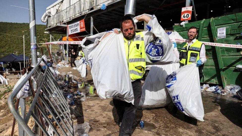 A rescue worker carries plastic bags with hats of Orthodox Jews