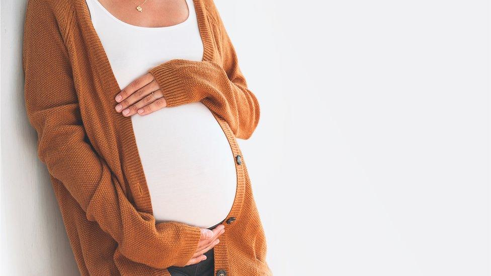 Pregnant woman with her hands around her belly