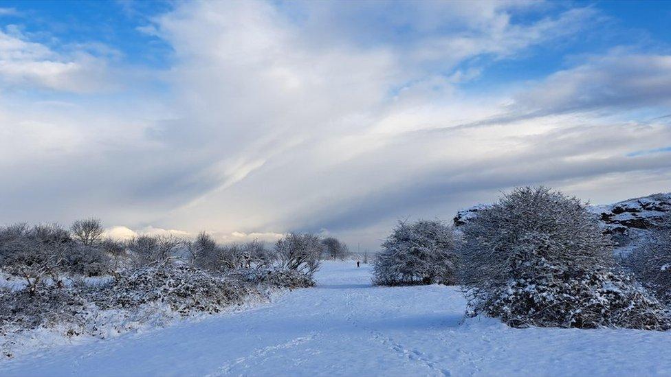 A snowy fields under a sky of broken cloud