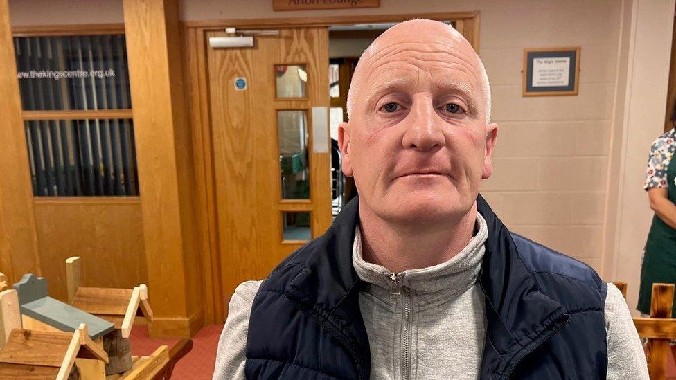 Image of Gary Woodcock, wearing a blue gilet and grey jumper, in the foodbank.