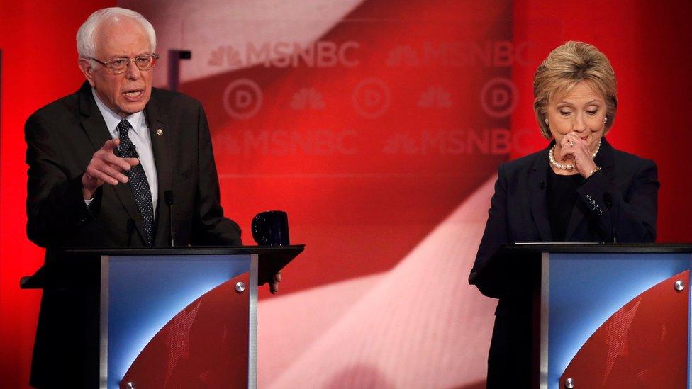 Hillary Clinton looking down as Bernie Sanders speaks