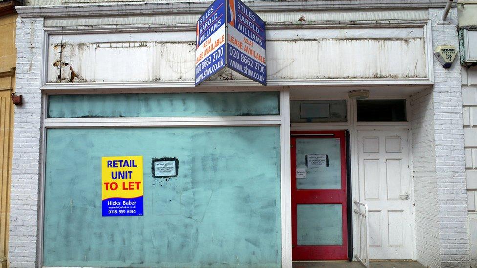 An empty retail unit with a property agency sign in Reading, England