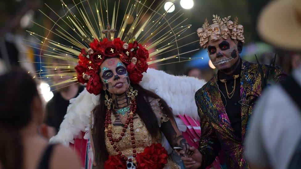 A couple in full day-of-the-dead dress including light up headband