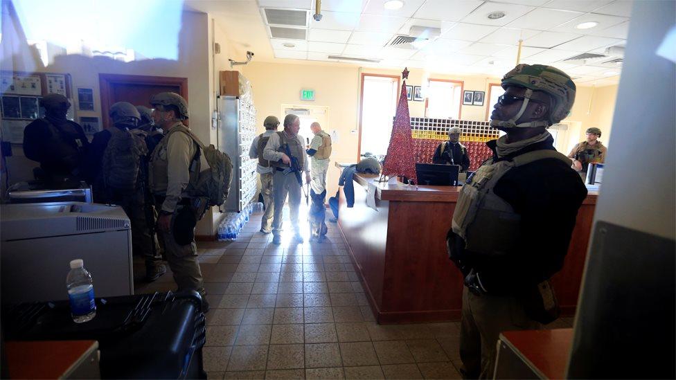 US embassy security personnel seen through a glass window during a protest in Baghdad, Iraq (31 December 2019)