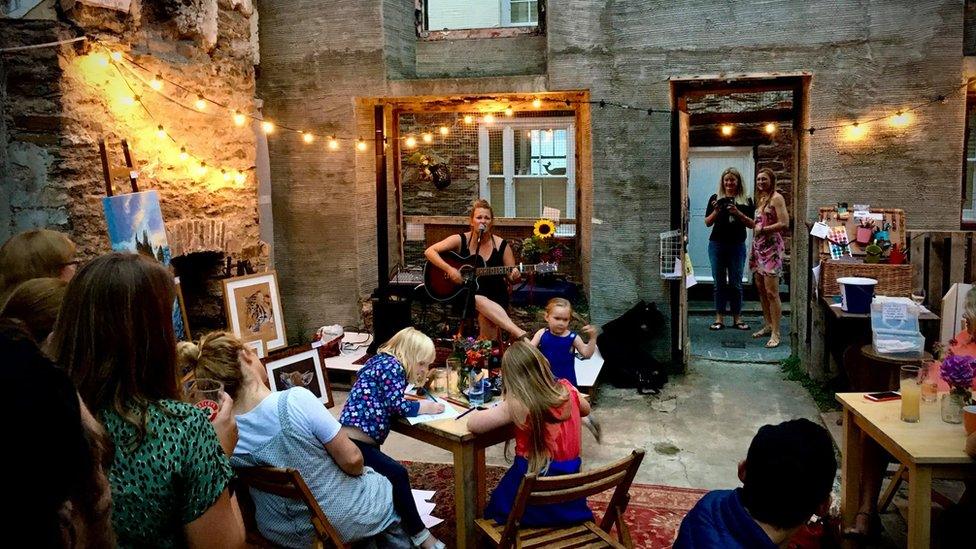 Woman plays guitar in a pub