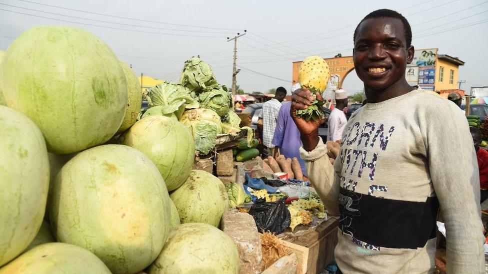 A roadside vendor holds fruit displayed for sale in Lagos, Nigeria's commercial capital, on March 14, 2022