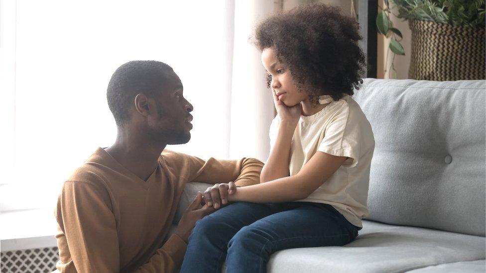 child sat on sofa talking to dad