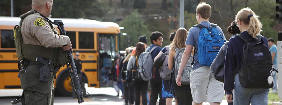 An officer watches student evacuate school