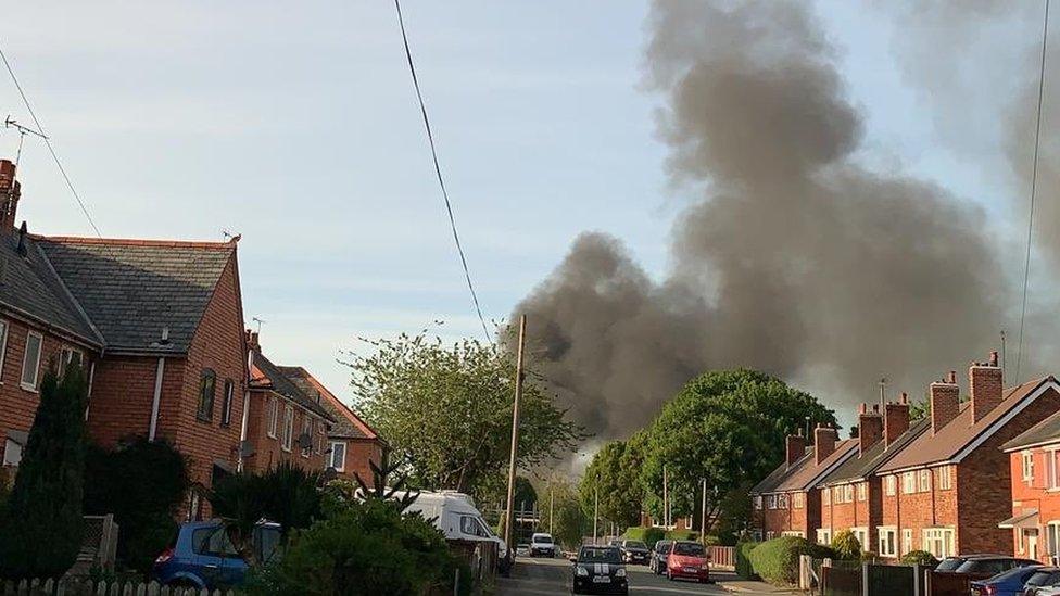 Thick black smoke can be seen rising from the scene of the fire