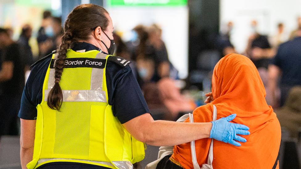 A member of Border Force staff assisting an Afghan refugee on her arrival on an evacuation flight from Afghanistan