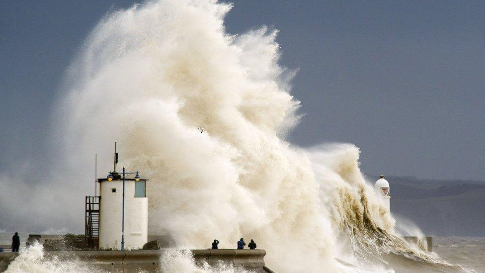 Spectators watch as waves break over the harbour wall at Porthcawl