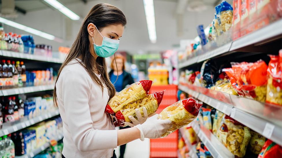 Woman in mask buying pasta