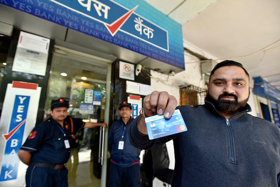 A Yes Bank account-holder shows his debit card outside the Gole Market branch, in New Delhi, India, on Friday, March 6, 2020.