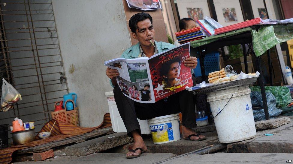 A man reading a newspaper on the roadside in Yangon