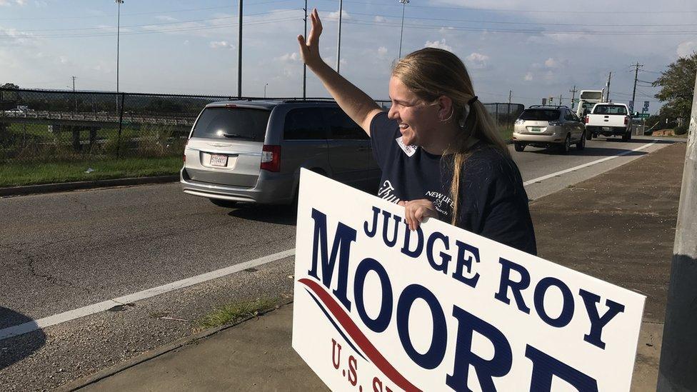 Eva Dastrow waves at cars in Montgomery, Alabama