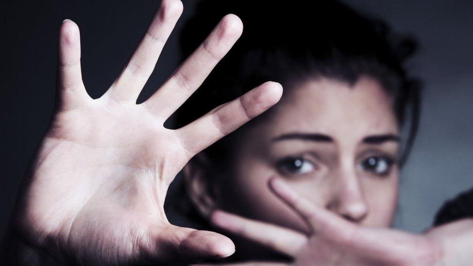 Frightened woman shielding her face with her hands.