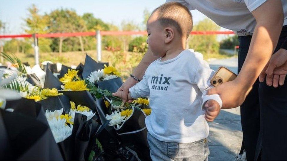 A toddler lays flowers in Jiuzi