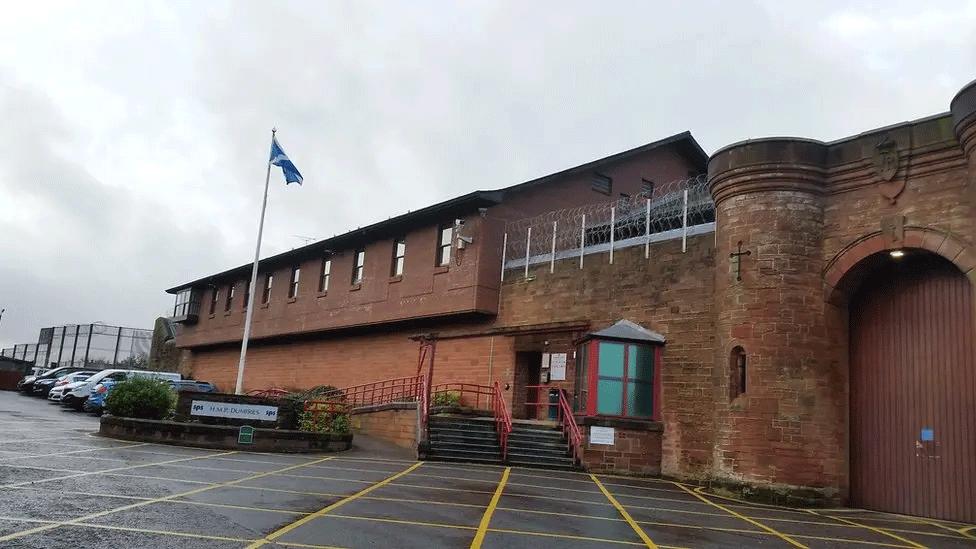 A brick prison building with a Scottish saltire flying outside on a grey day