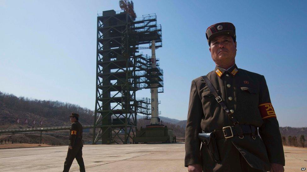 North Korean soldiers stands in front of the country"s Unha-3 rocket,