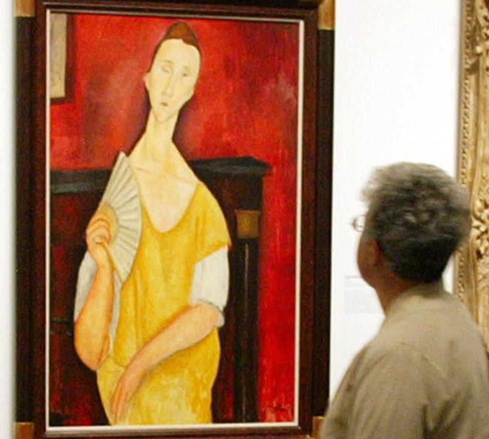 A visitor looking at the painting La femme à l'éventail (Woman with a Fan) by Amedeo Modigliani