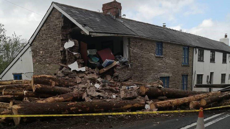 The house missing a corner with timber in front