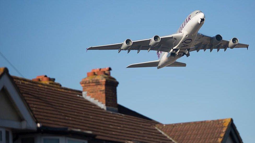 An aircraft flies over homes in Feltham after taking off from Heathrow Airport