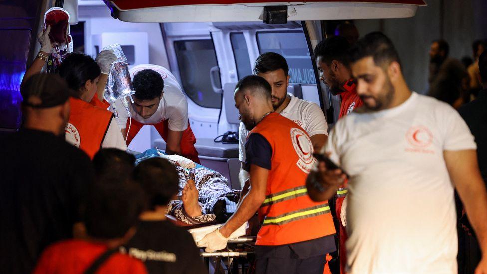 A wounded person is carried on a stretcher by medics from an ambulance in Beirut