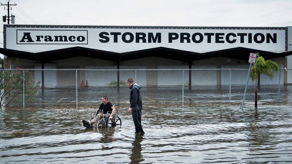 Brad Matheney offers help to a man in a wheelchair in a flooded street in Galveston